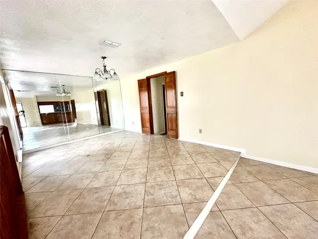 a view of a hallway with wooden floor and chandelier