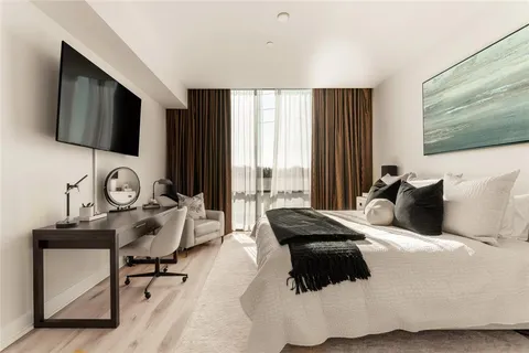 a bedroom with bed and a large mirror next to a window