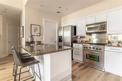 a kitchen with stainless steel appliances granite countertop a stove top oven a sink and a refrigerator