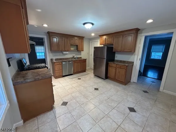 a open kitchen with stainless steel appliances granite countertop a refrigerator oven a sink dishwasher and a black countertops with wooden floor