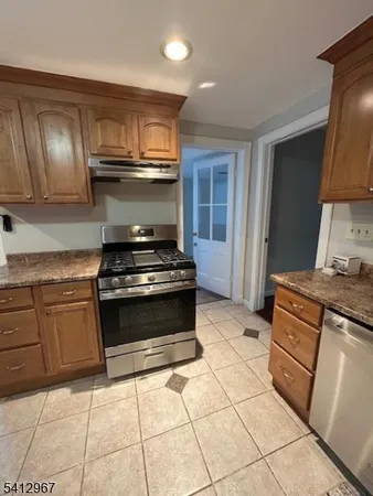 a kitchen with granite countertop a stove a sink and a refrigerator