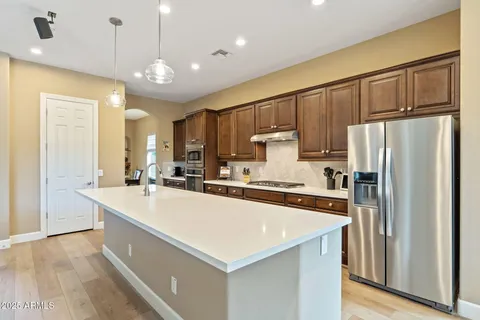 a kitchen with stainless steel appliances a sink a stove a refrigerator cabinets and wooden floor