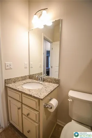 a bathroom with a granite countertop toilet sink and mirror
