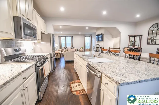 a large kitchen with stainless steel appliances granite countertop a lot of counter space and wooden floor