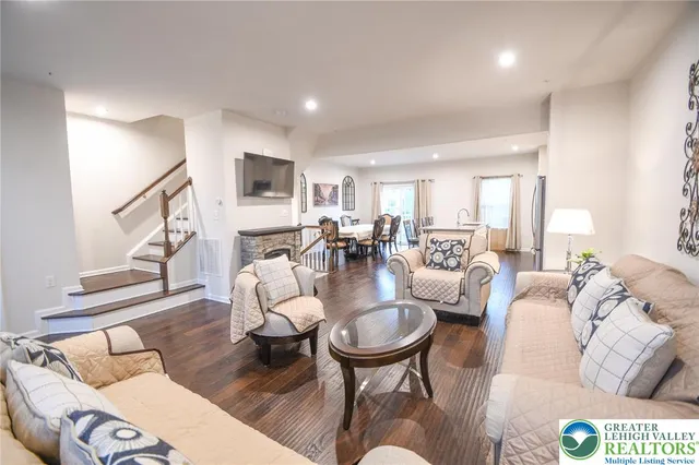 a living room with furniture kitchen view and a wooden floor
