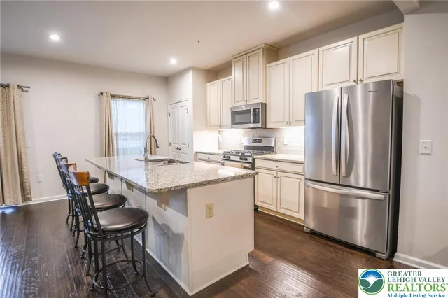 a kitchen with stainless steel appliances granite countertop a refrigerator a sink dishwasher a stove and a refrigerator with wooden floor