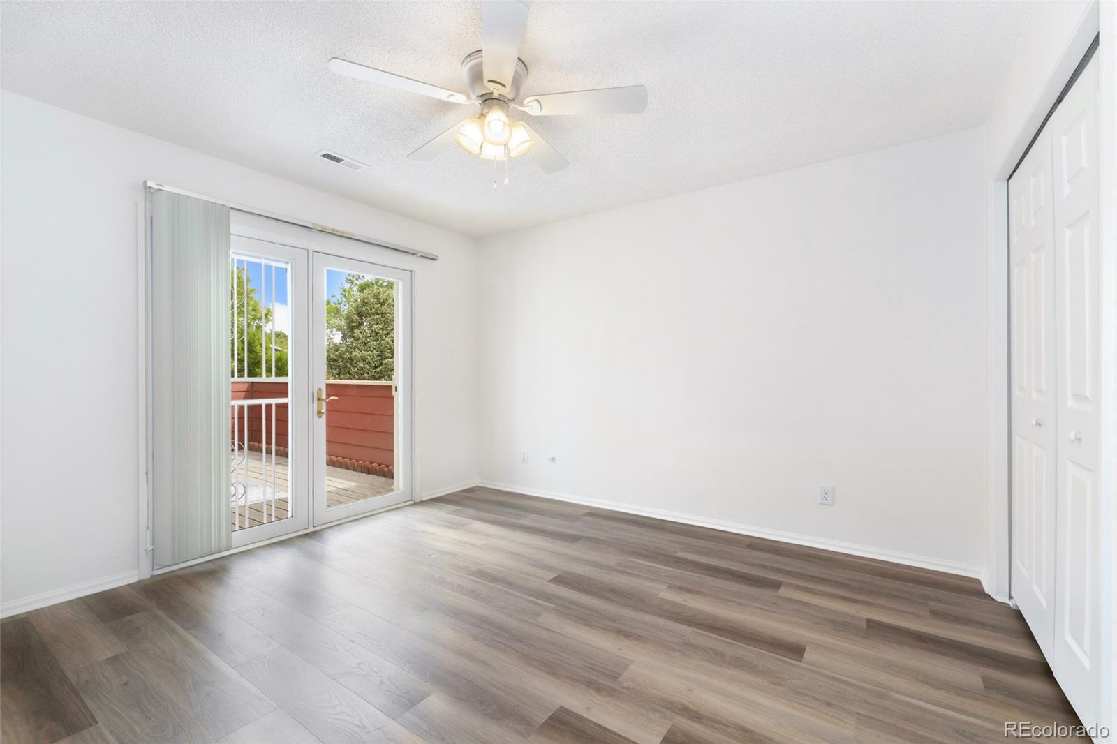 8417 Everett Way, Unit E Arvada, CO 80005 - Photo 12 of 36 an empty room with wooden floor fan and windows