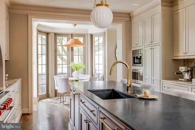 a kitchen with stainless steel appliances granite countertop a sink a stove and white cabinets next to a window