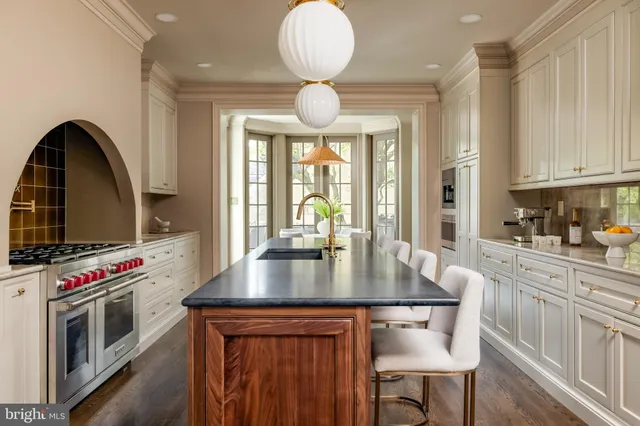 a kitchen with stainless steel appliances granite countertop a stove top oven a sink a dining table and chairs with wooden floor