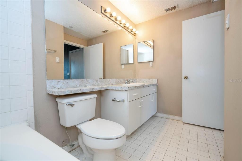 5572 Metrowest Boulevard, Unit 309 Orlando, FL 32811 - Photo 13 of 66 a bathroom with a granite countertop toilet sink and mirror