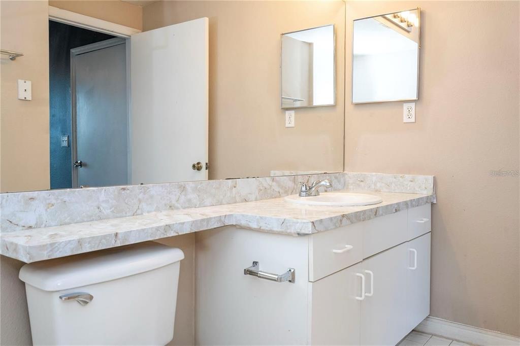 5572 Metrowest Boulevard, Unit 309 Orlando, FL 32811 - Photo 15 of 66 a bathroom with a granite countertop sink and a mirror