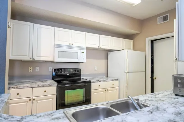a kitchen with granite countertop white cabinets and stainless steel appliances