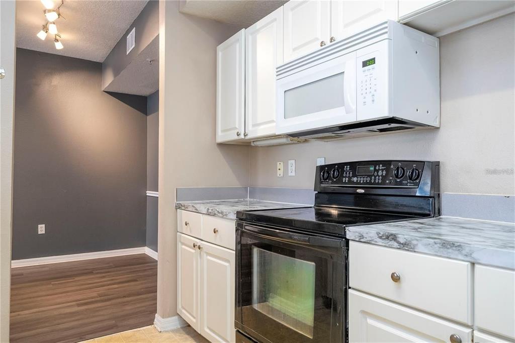 5572 Metrowest Boulevard, Unit 309 Orlando, FL 32811 - Photo 29 of 66 a kitchen with granite countertop white cabinets and stainless steel appliances