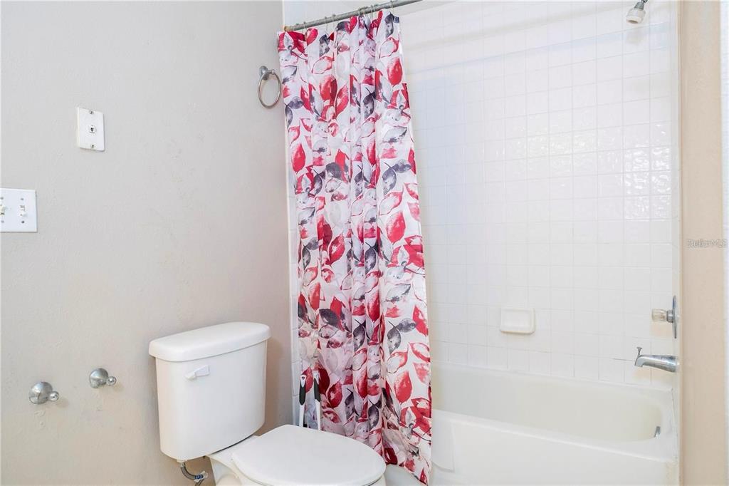 5572 Metrowest Boulevard, Unit 309 Orlando, FL 32811 - Photo 42 of 66 a white toilet sitting next to a shower curtain