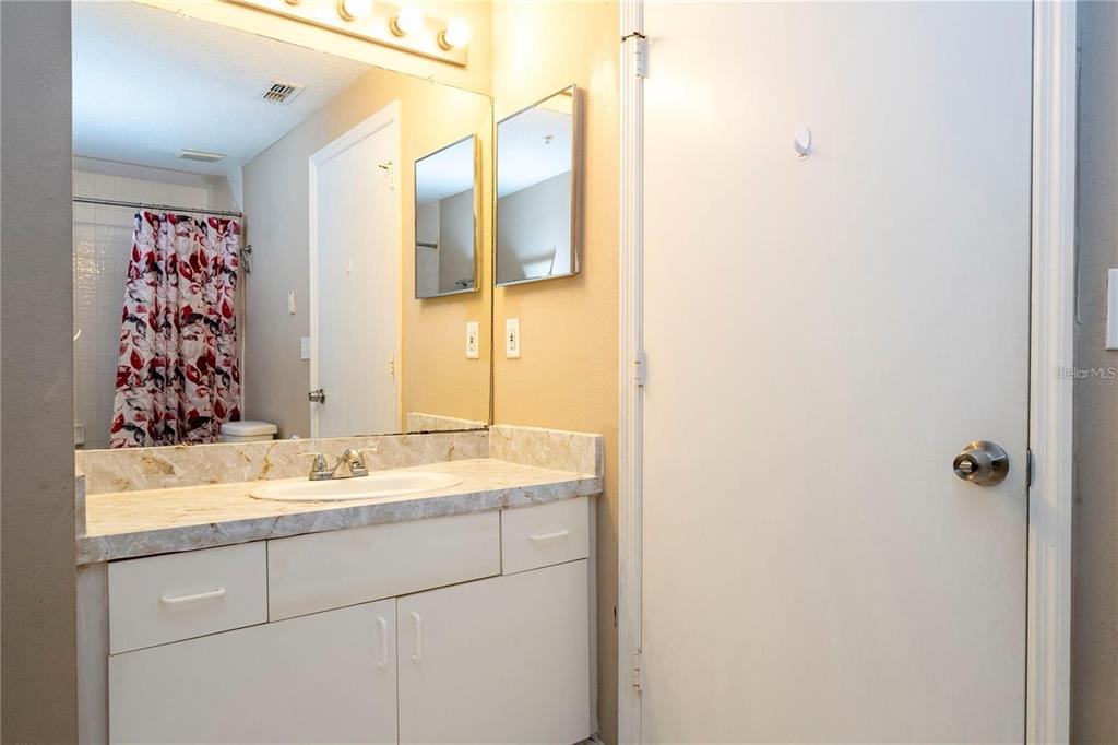 5572 Metrowest Boulevard, Unit 309 Orlando, FL 32811 - Photo 44 of 66 a bathroom with a granite countertop sink and a mirror