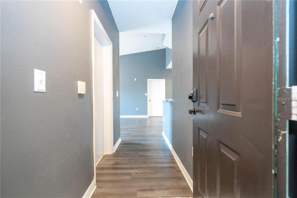 5572 Metrowest Boulevard, Unit 309 Orlando, FL 32811 - Photo 5 of 66 a view of a hallway with wooden floor and staircase