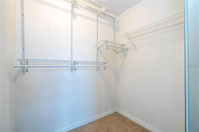 an empty room with wooden floor windows and fan