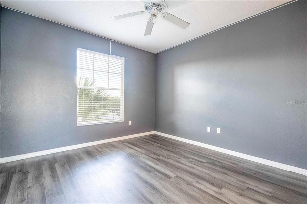 5572 Metrowest Boulevard, Unit 309 Orlando, FL 32811 - Photo 8 of 66 an empty room with wooden floor windows and fan