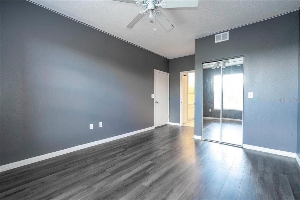 5572 Metrowest Boulevard, Unit 309 Orlando, FL 32811 - Photo 9 of 66 an empty room with wooden floor and fan