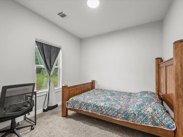 a bedroom with a bed table and chair