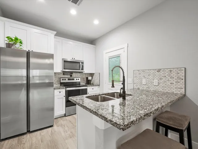a kitchen with stainless steel appliances granite countertop a sink refrigerator and microwave