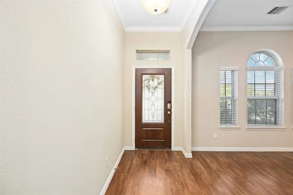 an empty room with wooden floor cabinet and windows