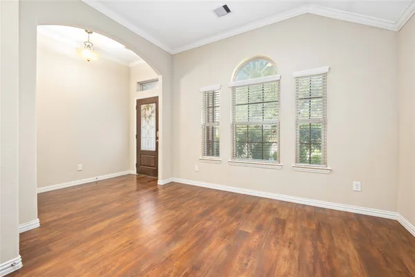 an empty room with wooden floor cabinet and windows