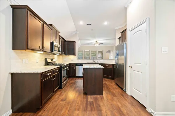 a kitchen with wooden floors and wooden cabinets