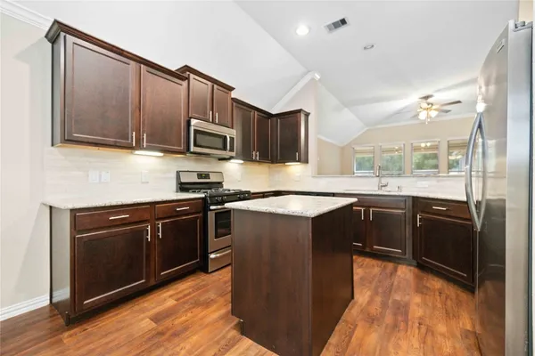 a kitchen with stainless steel appliances granite countertop wooden cabinets a stove a sink and a microwave