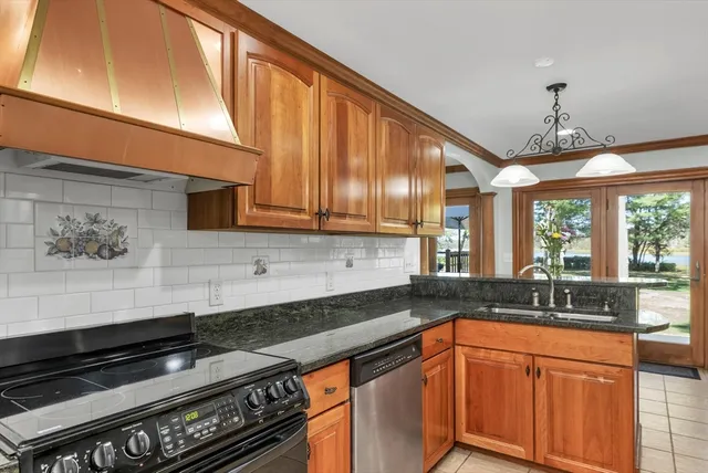 a kitchen with granite countertop stainless steel appliances a sink stove and cabinets