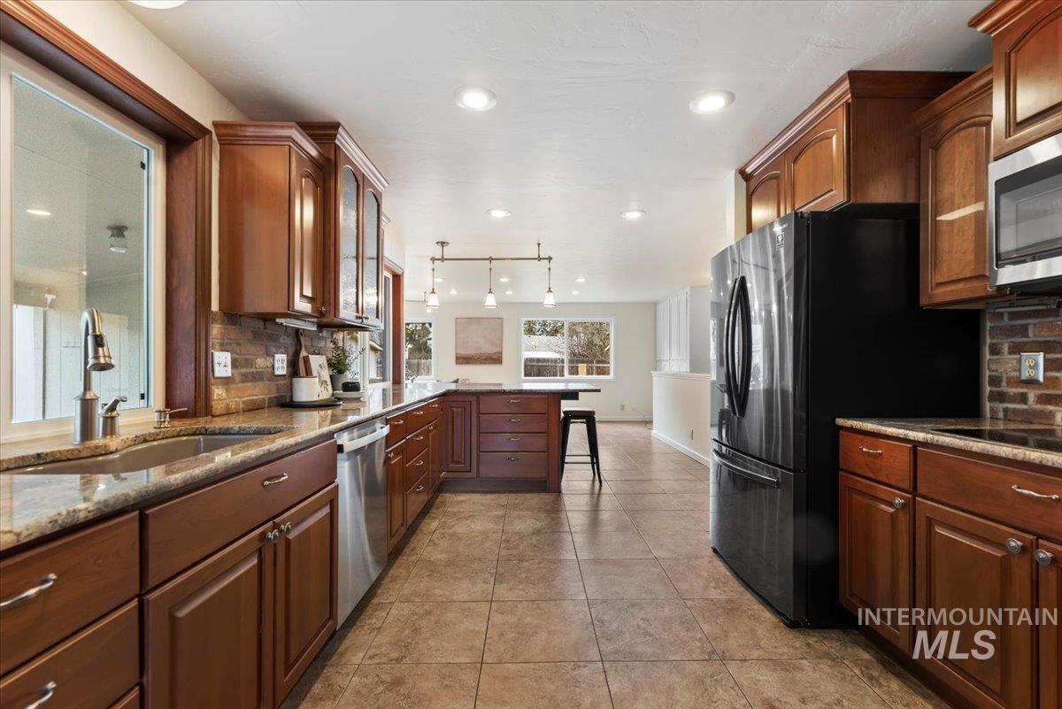 4297 Nystrom Way Boise, ID 83713 - Photo 7 of 50 Kitchen featuring tasteful brick backsplash, a peninsula, a breakfast bar, stone countertops, and stainless steel appliances