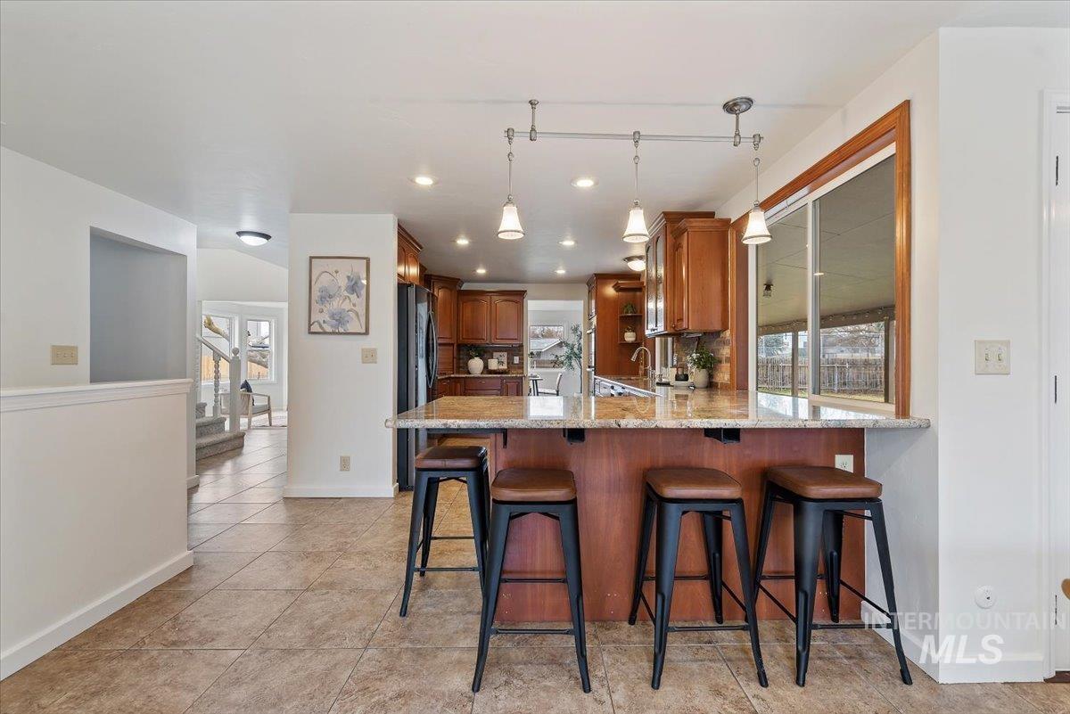 4297 Nystrom Way Boise, ID 83713 - Photo 9 of 50 Kitchen with wood finish cabinetry, a breakfast bar, light stone countertops, and a peninsula