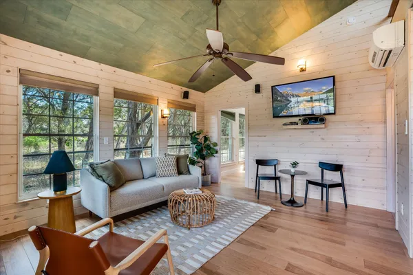 a living room with furniture a flat screen tv and a floor to ceiling window