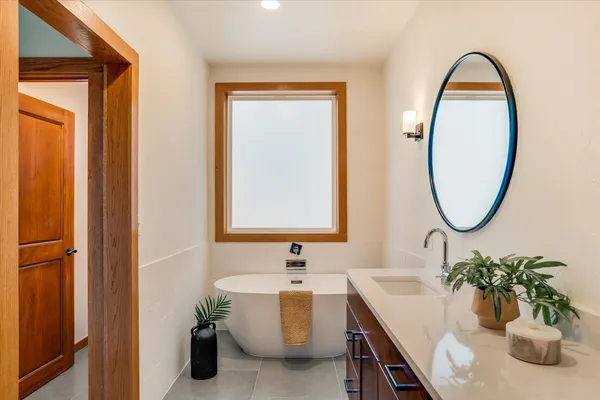 a bathroom with a tub sink and mirror