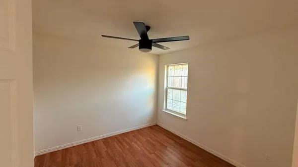 an empty room with windows and fan
