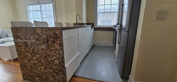 a bathroom with a granite countertop sink a window and a shower