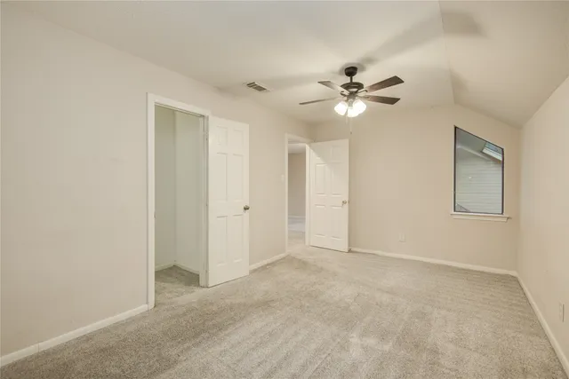 an empty room with windows and fan