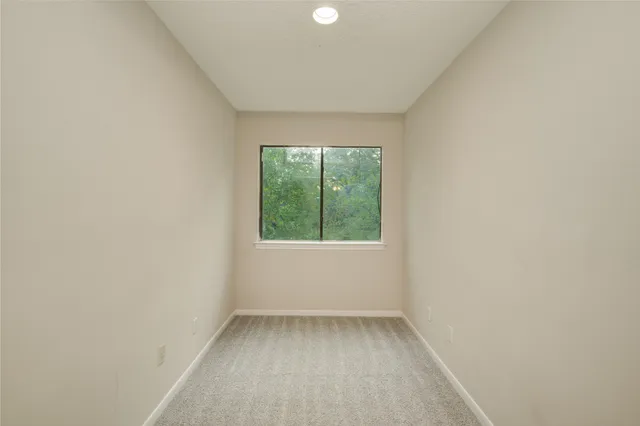 an empty room with a chandelier fan and windows