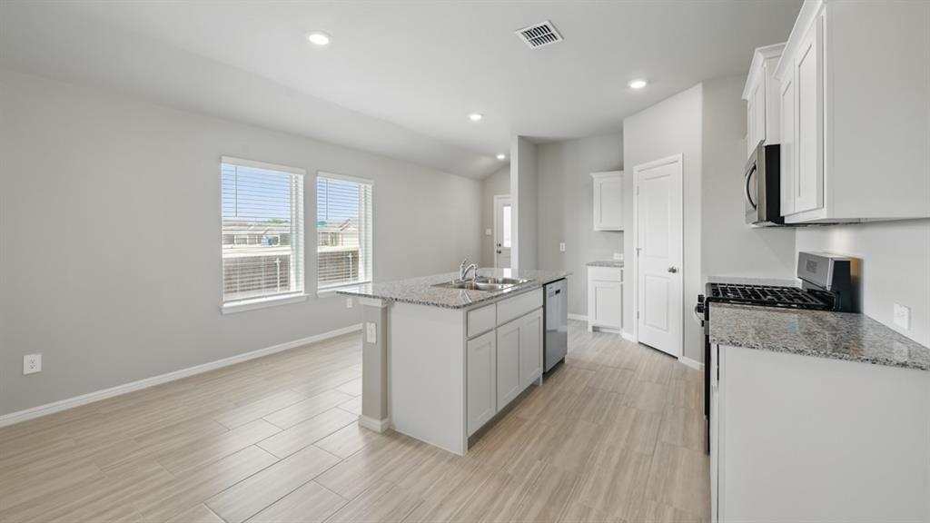 172 Mojave Road Boyd, TX 76023 - Photo 5 of 40 a kitchen with granite countertop a stove top oven a sink a refrigerator and white cabinets with wooden floor