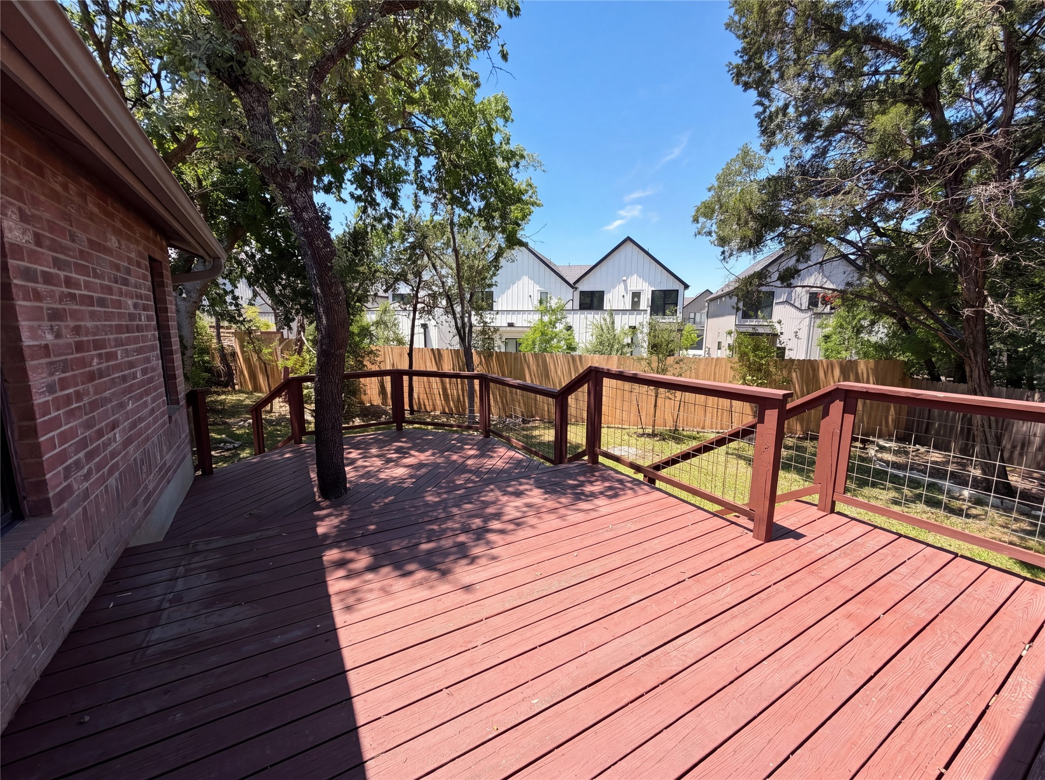 1111 North Riviera Circle Cedar Park, TX 78613 - Photo 16 of 17 Expansive wood-finish deck with integrated mature tree, surrounded by a wood privacy fence and wire-panel railing