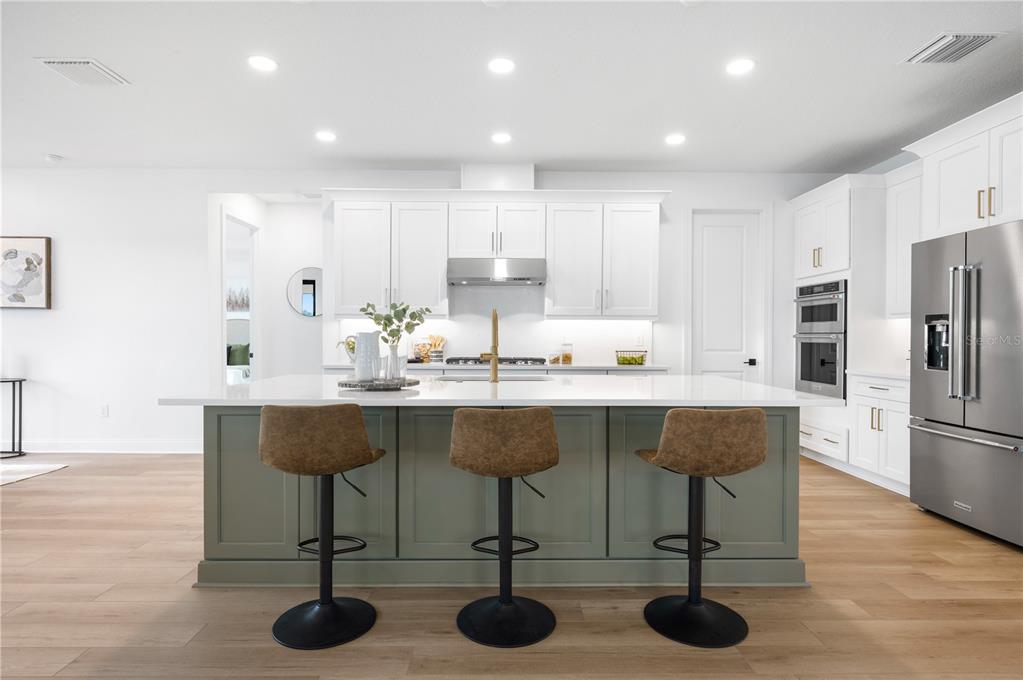 5856 Freestone Circle Apollo Beach, FL 33572 - Photo 8 of 33 a kitchen with stainless steel appliances kitchen island granite countertop a table chairs sink and cabinets
