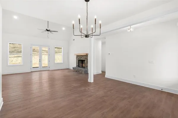 an empty room with wooden floor fireplace and windows