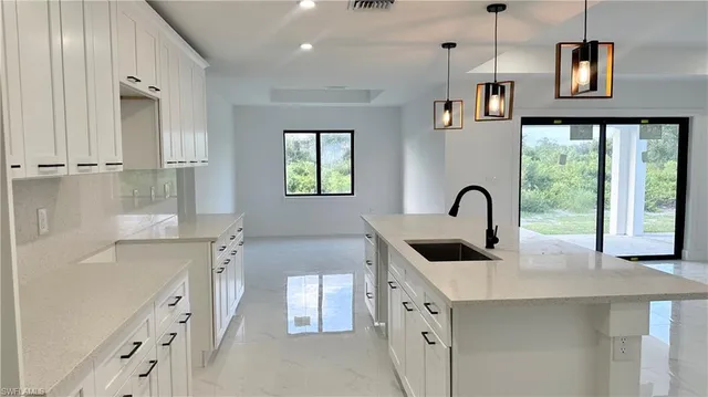 a kitchen with stainless steel appliances kitchen island a white counter top a sink a refrigerator a window and a mirror