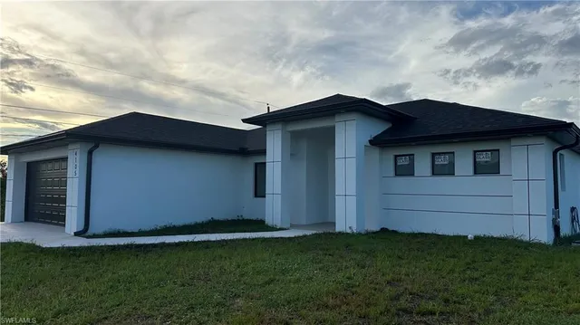 a view of a house with a small yard and garage