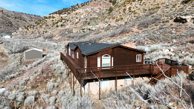 7500 Spring Canyon Road Helper, UT 84526 - Photo 6 of 83 View of home's exterior featuring a deck with mountain view, a shingled roof, and log veneer siding