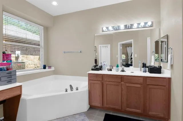 a bathroom with a bathtub a double vanity sink and mirror