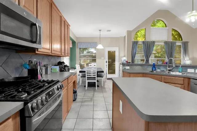 a kitchen with stainless steel appliances granite countertop a sink a stove and a wooden cabinets