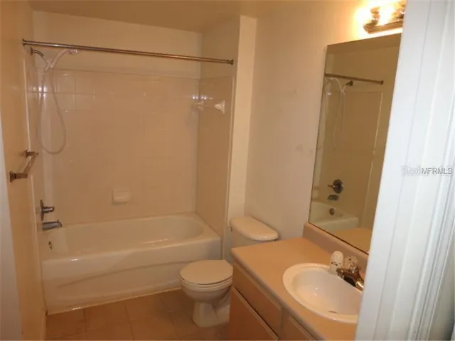 a bathroom with a granite countertop bathtub shower sink vanity and toilet