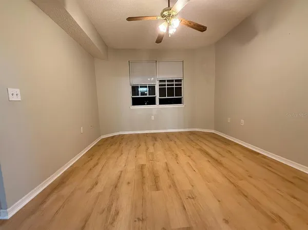 a view of empty room with wooden floor and fan