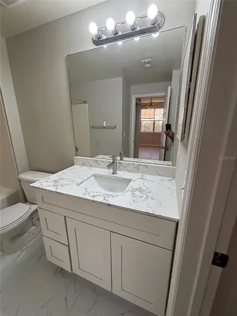 a bathroom with a granite countertop sink a toilet and a bathtub